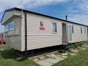 a white trailer with a sign on the side of it at Caledonian Caravan in Jaywick Sands