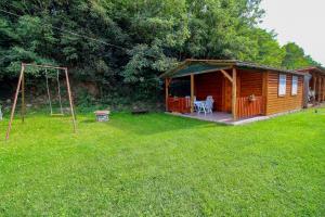 ein Blockhaus mit einem Spielplatz und einer Schaukel in der Unterkunft Horváth Vendégház in Mónosbél