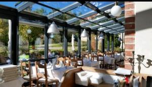 a restaurant with white tables and chairs and windows at Ferienapartment Wiese & Meer auf Rügen in Neddesitz