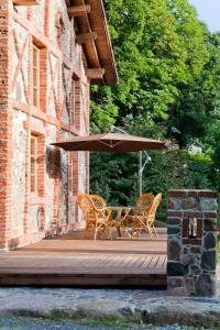 Duas cadeiras e uma mesa com um guarda-sol no deque em Linnumaja Guesthouse em Uulu