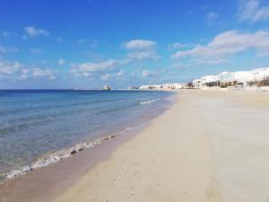 a beach with the ocean and buildings in the background at Antica Masseria Ficazzana - Tenuta in Marina di Pescoluse