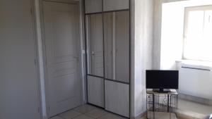 Habitación con armario, TV y puerta. en Le Petit St Jacques en Le Puy-en-Velay