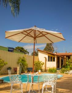 a table with an umbrella next to a pool at Pousada Luz do Sol in Carrancas