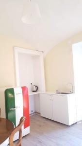 W kuchni znajduje się czerwona i zielona lodówka oraz stół. w obiekcie Palazzo Colombino Suite&Residence w mieście Giaveno
