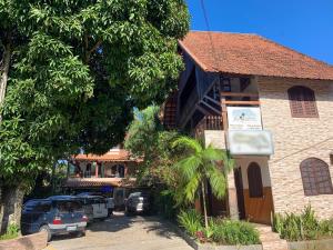 a building with cars parked in a parking lot at Chalé do Recanto in Lumiar