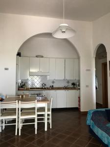 a kitchen with white cabinets and a table and chairs at Villetta Patrizia in Santa Maria