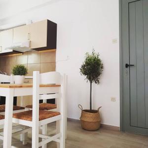 una cucina bianca con tavolo e pianta in vaso di Greekowl apartments a Città di Skiathos