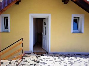 a yellow house with a white door and a porch at Apartman Majetić in Seliste Dreznicko