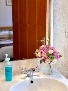 un jarrón de flores sentado en el lavabo del baño en Atlantic Guest House en Donegal