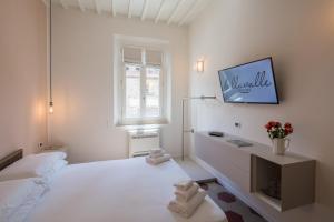 a white bedroom with a bed and a tv on a wall at Bellavalle ROOMS Vinci Florence Tuscany in Vinci