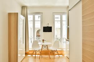 ein Esszimmer mit einem Tisch und weißen Stühlen in der Unterkunft Nice Home - Studios Lido in Nizza