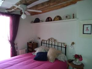 1 dormitorio con 1 cama con sábanas moradas y ventilador en VEN GAVINO en Ibdes
