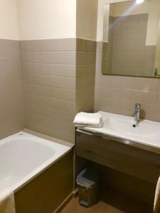 een badkamer met een wastafel en een bad bij Les résidences du port appartements meublés in Porto Ota