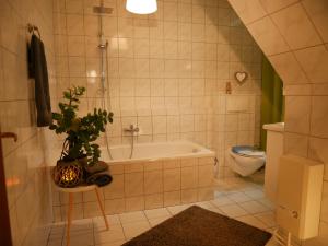 e bagno con vasca, servizi igienici e pianta. di Ferienwohnung Wusterwitz a Wusterwitz