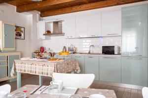 una cucina con tavolo e armadietti bianchi di La Casa di Santino a Comacchio
