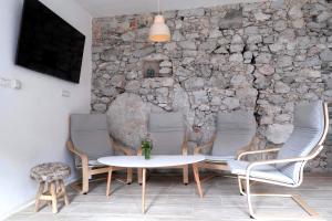 Habitación con mesa, sillas y pared de piedra. en Premium Hostel Kobarid, en Kobarid