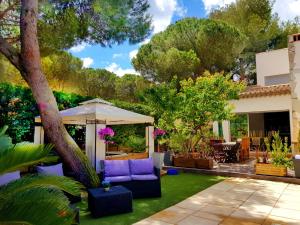 a backyard with a blue couch and a white umbrella at Villa Aurelie in Cap d'Agde