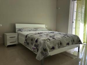 a bedroom with a bed and a night stand and a window at Mali i Robit Beachfront Apartment in Golem