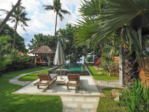 a backyard with two chairs and an umbrella and a pool at Octopus Villas in Tejakula