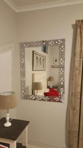 een spiegel aan een muur in een kamer met een tafel bij Anas Inn in Walvis Bay