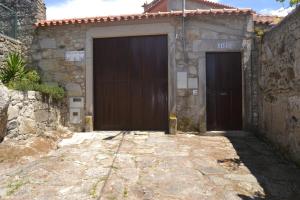 two brown doors on a stone building with a sidewalk at Quinta do Real - Casa de Campo in Viana do Castelo