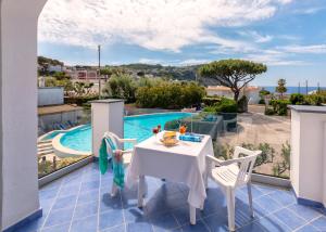 a balcony with a table and chairs and a swimming pool at Hotel Costa Citara in Ischia