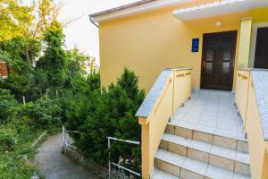 a yellow house with stairs leading to a door at Apartments Ines in Baška