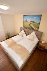 ein Schlafzimmer mit einem großen weißen Bett mit einem Gemälde an der Wand in der Unterkunft Bären in Hechingen