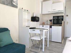 uma pequena cozinha com uma pequena mesa e uma cozinha branca em Studio rénové balcon ensoleillé et calme em La Londe-les-Maures