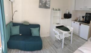 a living room with a couch and a table and a kitchen at Studio rénové balcon ensoleillé et calme in La Londe-les-Maures