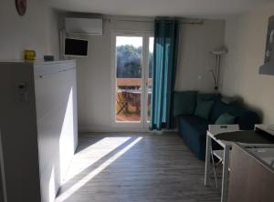 a living room with a blue couch and a window at Studio rénové balcon ensoleillé et calme in La Londe-les-Maures