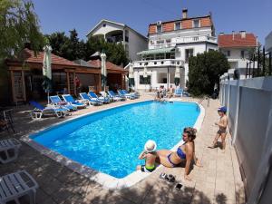 eine Gruppe von Personen, die um einen Pool stehen in der Unterkunft Garni Hotel Panorama Lux in Niš
