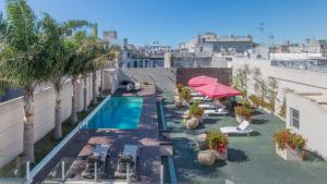 an apartment with a swimming pool and tables and umbrellas at Don Boutique Hotel Montevideo in Montevideo