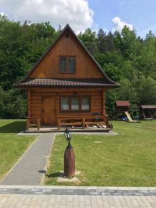 una cabaña de madera con un banco en el césped en Ośrodek Niezapominajka, en Górzanka