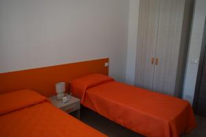 two beds in a room with orange sheets at Acqua Chiara Appartamenti in San Vito lo Capo