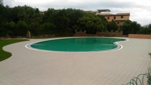 a swimming pool in a yard with a tiled patio at Appartamento in Rudargia Residence in Porto Rotondo