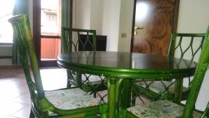 a green table and two chairs with a table and a door at Appartamento in Rudargia Residence in Porto Rotondo +10 photos