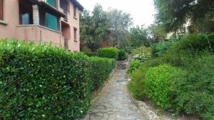 a stone path in front of a building next to a hedge at Appartamento in Rudargia Residence in Porto Rotondo