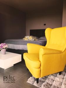 Apartma Sobe Pulec في دوبروفو: غرفة نوم وكرسي اصفر وسرير