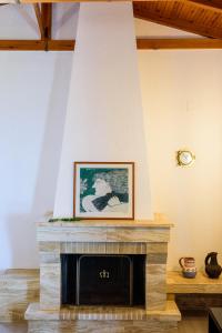 a living room with a stone fireplace with a picture at Finisia House in Elia Laconias