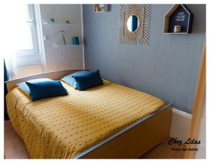 een bed met twee blauwe kussens in een kamer bij Chez Lilas 150m Plage in Duinkerke