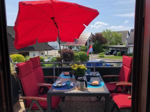 ein Tisch mit einem roten Sonnenschirm auf einem Balkon in der Unterkunft Nordbrise in Büsum