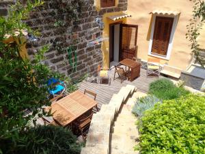 une terrasse en bois avec des chaises et des tables en face d'un bâtiment dans l'établissement Baglio Antico Forno, à Ustica