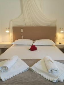 a bed with two towels and a rose on it at Andreas and Petrinela Rooms in Triovasálos