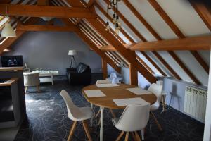 een eetkamer met een houten tafel en witte stoelen bij Le gite du Frene in Poses