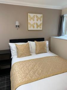 Waverley Inn Lodge في دينغول: غرفة نوم مع سرير مع ملاءات بيضاء والفراشات على الحائط