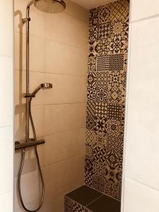 a bathroom with a shower with a tile wall at Les Chambres d'Hotes chez Alisa et Daniel in Sarlat-la-Canéda