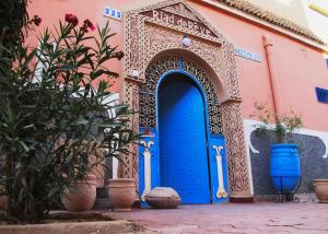 niebieskie drzwi na różowym budynku z roślinami w obiekcie Riad De Rêve w mieście Zakura