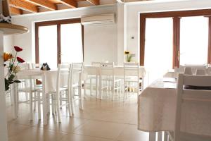 a dining room with white chairs and tables and windows at Paglia&Fieno in Rivoli Veronese