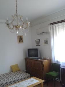 a bedroom with a chandelier and a bed and a tv at Sarkadi Apartman in Hajdúszoboszló